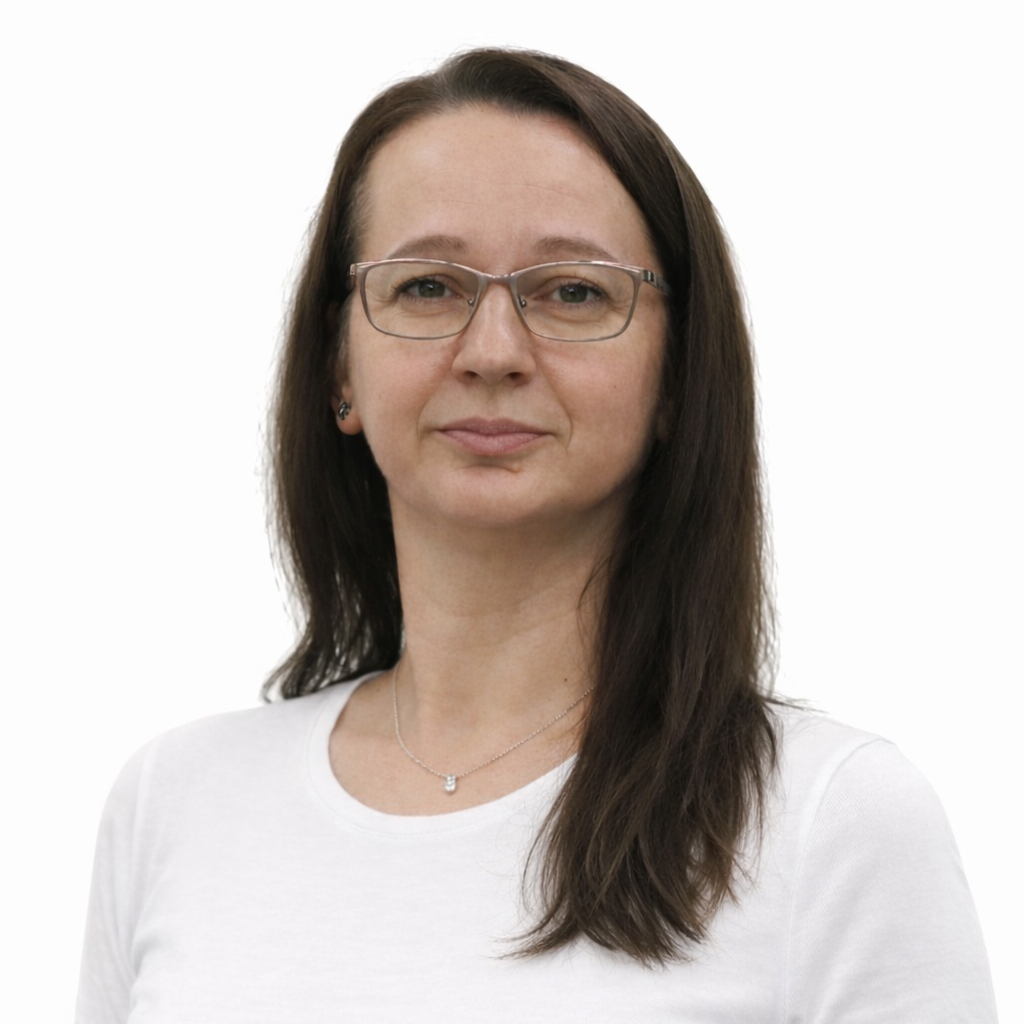 Portrait of a woman with brown hair, glasses, and a white shirt looking at the camera.